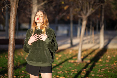 Smiling young woman standing at park during winter