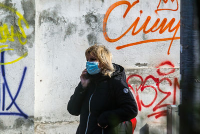 Full length of woman standing against graffiti wall