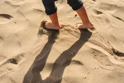 Low section of child standing on sand