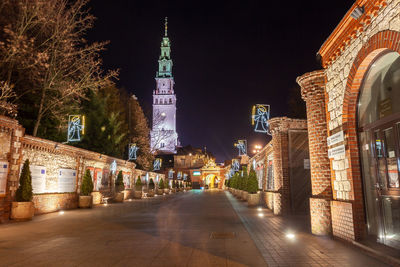 Illuminated street amidst buildings in city at night