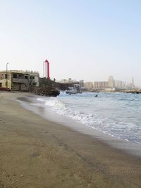 Scenic view of beach by buildings against clear sky