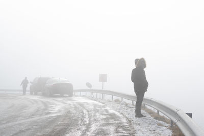 Man standing on snow covered road against fog