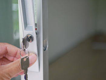 Cropped hands of person adjusting lock on glass door