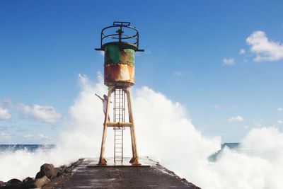 Lighthouse by sea against blue sky