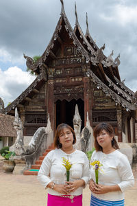 Portrait of sisters standing against temple