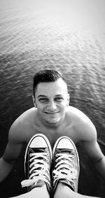 Portrait of smiling young man sitting against water