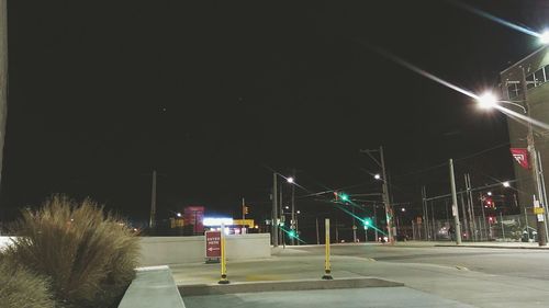 Illuminated road against sky at night