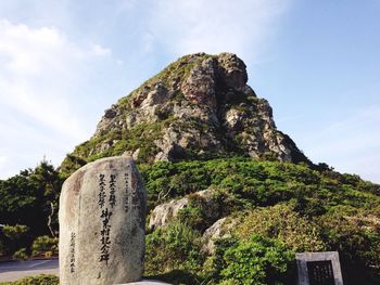 Low angle view of text on rock against hill