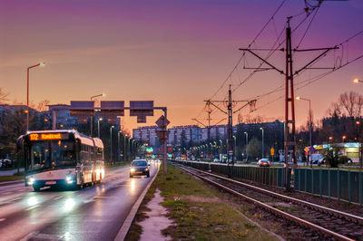 Cars on street in city against sky at sunset