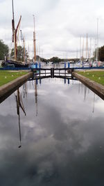 Sailboats moored at harbor against sky