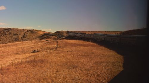 Train on road amidst field against sky