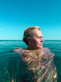 Portrait of woman swimming in sea against clear blue sky