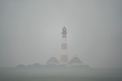 Lighthouse by sea against clear sky