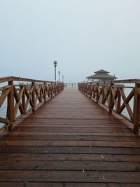 View of wooden pier leading to sea against clear sky