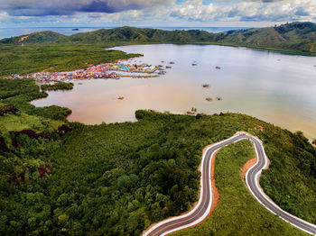 Aerial view of road and trees by lake against sky