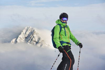 Man with umbrella on snow against sky