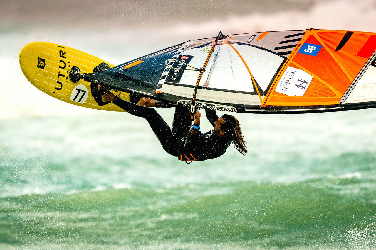 LOW ANGLE VIEW OF MAN PARAGLIDING IN SEA