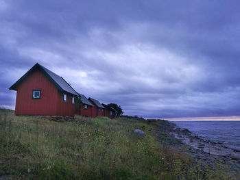 House on beach by building against sky