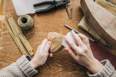 Cropped hands of woman carving wood at table
