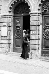 Side view of man and woman standing against building