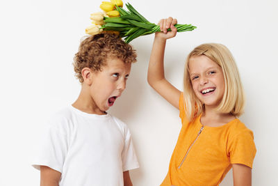 Portrait of girl holding bouquet on brothers head