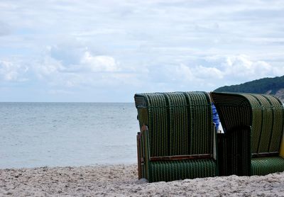 Deck chairs on beach against sky