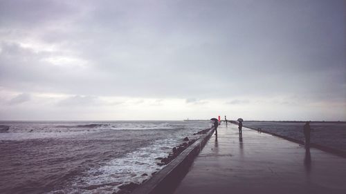 Pier on sea against cloudy sky