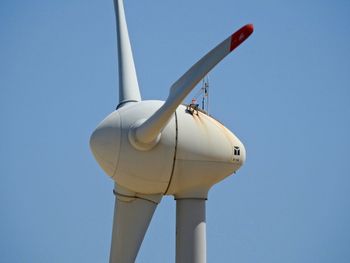 Low angle view of wind turbine against clear blue sky