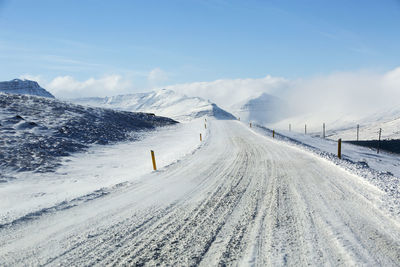 Snowy road with volcanic mountains in wintertime, iceland
