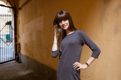 Cute young woman posing in the yard of a house , in a dress and a fitness bracelet on her arm