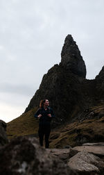 Rear view of man standing on rock against sky