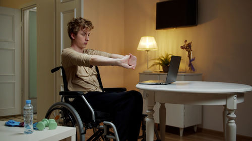 Young man stretching while vlogging at home