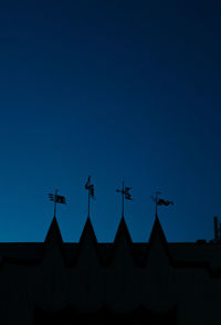 Low angle view of silhouette airplane flying against clear blue sky