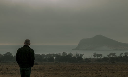Side view of adult man on seaside against rock and sky in winter. cabo de gata nature park, spain
