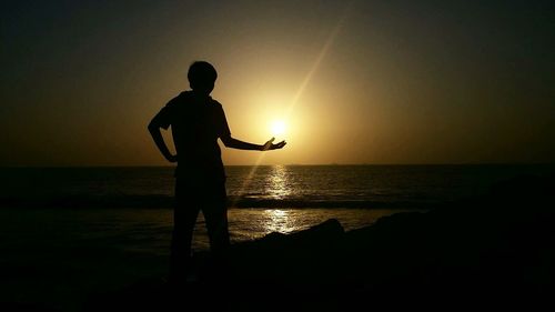 Silhouette of people on beach at sunset