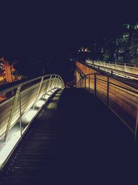 Footbridge over illuminated city against sky at night