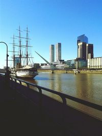 Bridge over river in city against clear sky