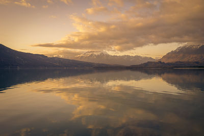 Scenic view of lake and mountains against sky during sunset