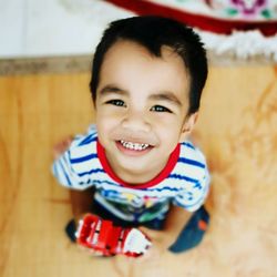 Portrait of smiling boy holding toy car at home