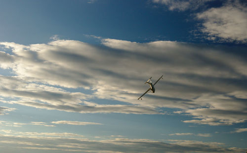 Low angle view of airplane flying in cloudy sky