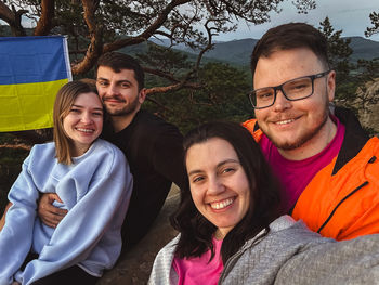 Portrait of smiling friends standing against trees