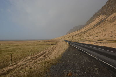 Road amidst land against sky