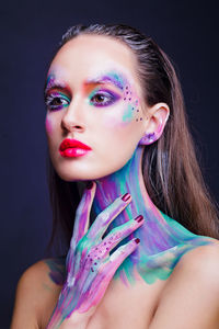 Beautiful young woman with multi colored bodypaint over black background