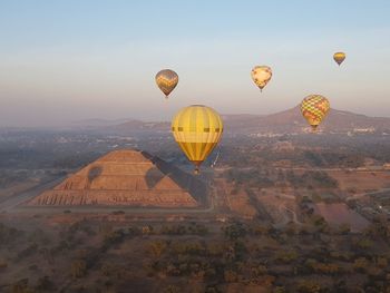 Hot air balloons flying over landscape and ancient pyramid