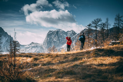 Rear view of people walking on mountain against sky