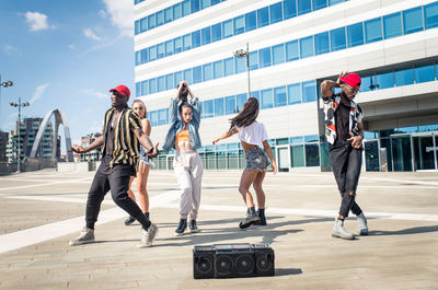 Friends dancing against building in city