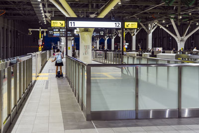 Rear view of woman with backpack standing at railroad station