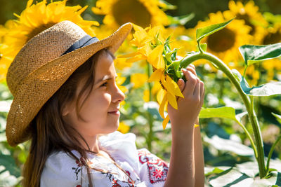 Cute smiling girl holding sunflower on field