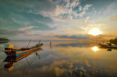 Sailboats in sea against sky during sunset