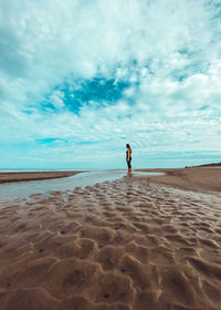 Full length of man standing on beach against sky